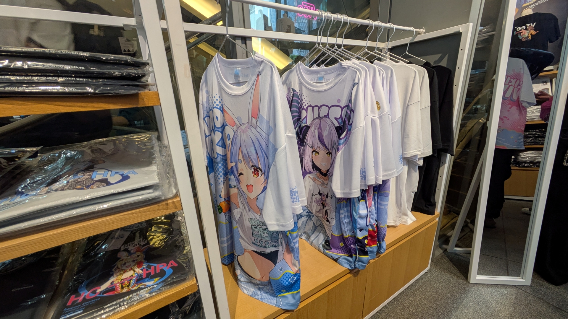 物販コーナーではKVを用いたグッズや過去に販売されたデザインTシャツ、「VTee」コラボTシャツなどが販売されている。「hololive Splash T-Party!」Tシャツは展示のみで現地販売は行なわれないため、購入はオンラインで行う必要がある