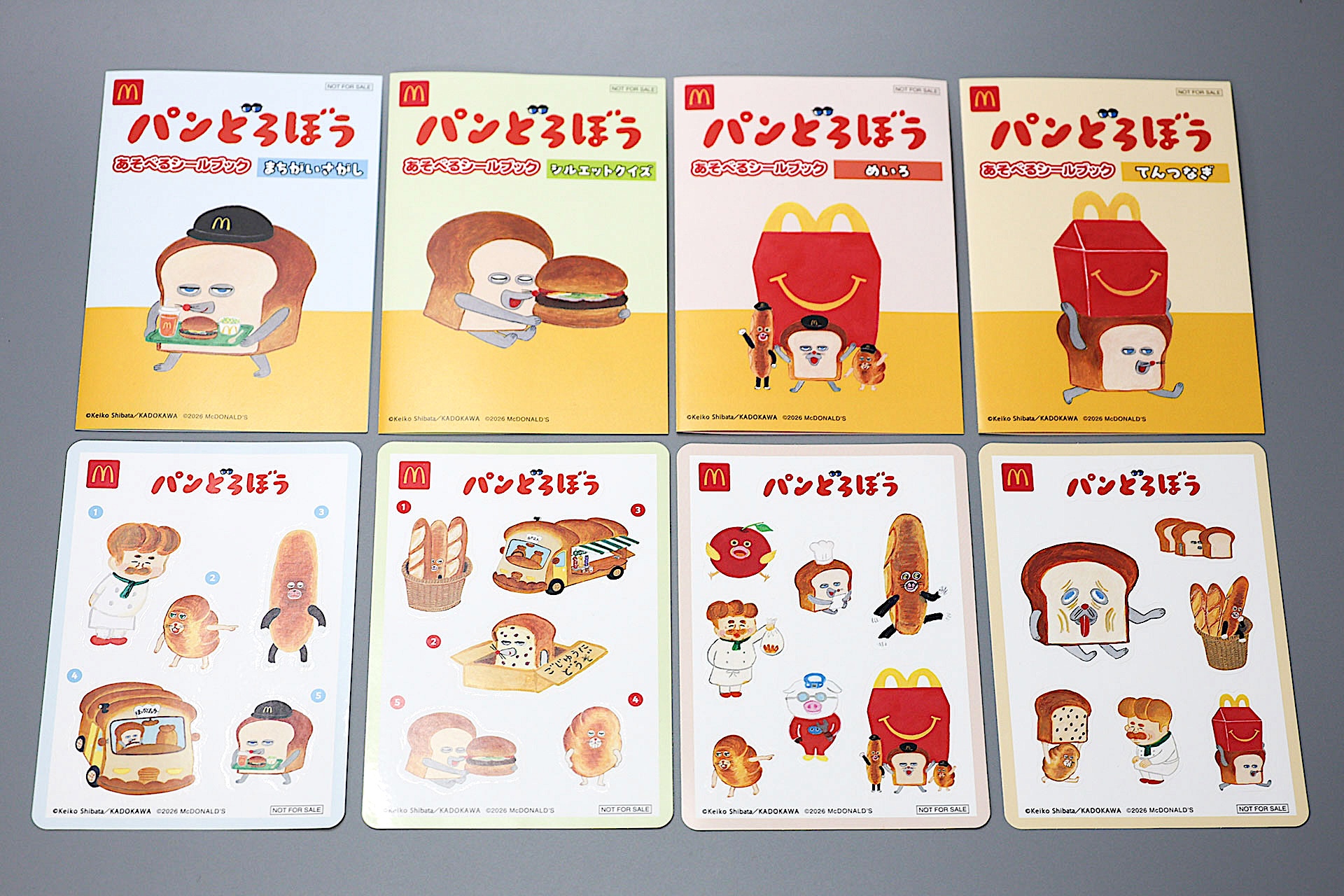 こちらがハッピーセット「パンどろぼう」(8月28日〜)に登場するおもちゃだ。写真左から「あそべるシールブック まちがいさがし」、「あそべるシールブック シルエットクイズ」、「あそべるシールブック めいろ」、「あそべるシールブック てんつなぎ」