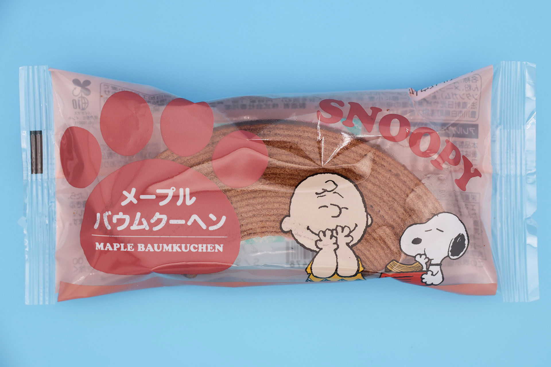 スヌーピーが食べ物を頬張る姿と、それを見ているチャーリー・ブラウンが描かれている
