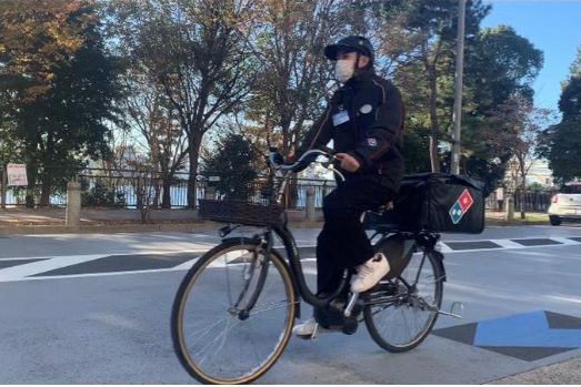 電動アシスト自転車で配達するドミノ・ピザのスタッフ