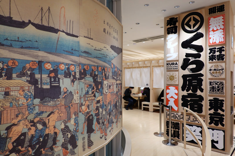 巨大浮世絵とくら寿司のさまざまなロゴを集めたロゴウォール