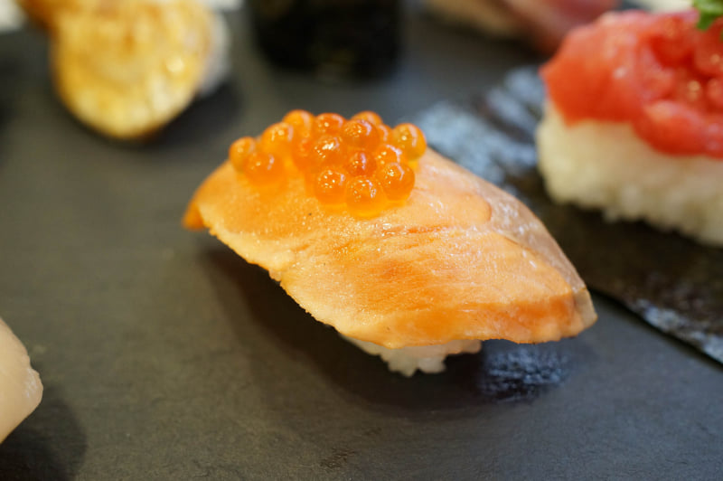 「郷土料理はらこ飯 だし醤油炙りサーモンいくらのせ」。実際の商品は2貫で提供