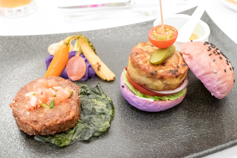 新作の「ハワイアン ルアウ ココナッツジンジャー風味のマッシュポテトを添えて」（左）と「アヒと海老のシーフードバーガー リリコイチリマヨネーズのソース」（右）