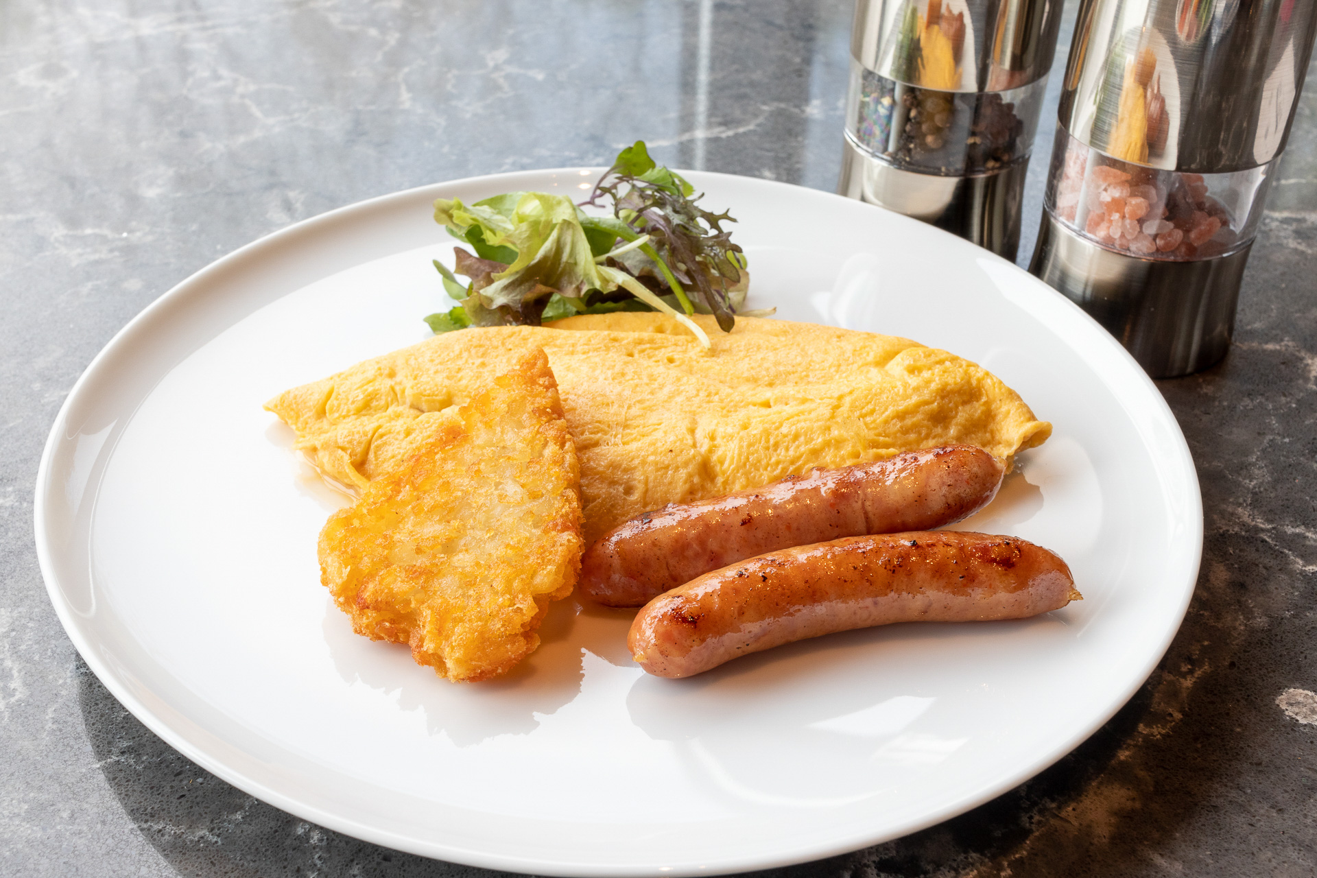 ゴーダチーズとマッシュルームを入れたオムレツ。付け合わせはハッシュドポテトとプライムポークのソーセージ