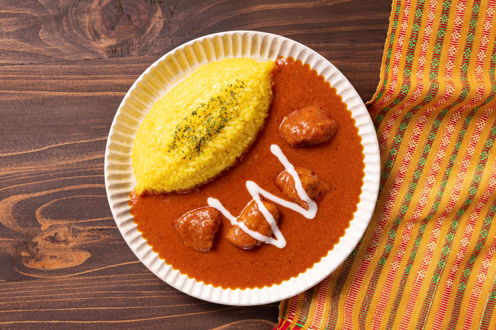 トマトの酸味とカルダモン・クミン・コリアンダーなどのさわやかなスパイスの風味が特徴のバターチキンカレー。バターを入れることでコクのある味わい。チキンはガラムマサラ、ヨーグルトなどに漬けこみ、スパイスの風味をより一層感じられる柔らかい食感に仕上げた