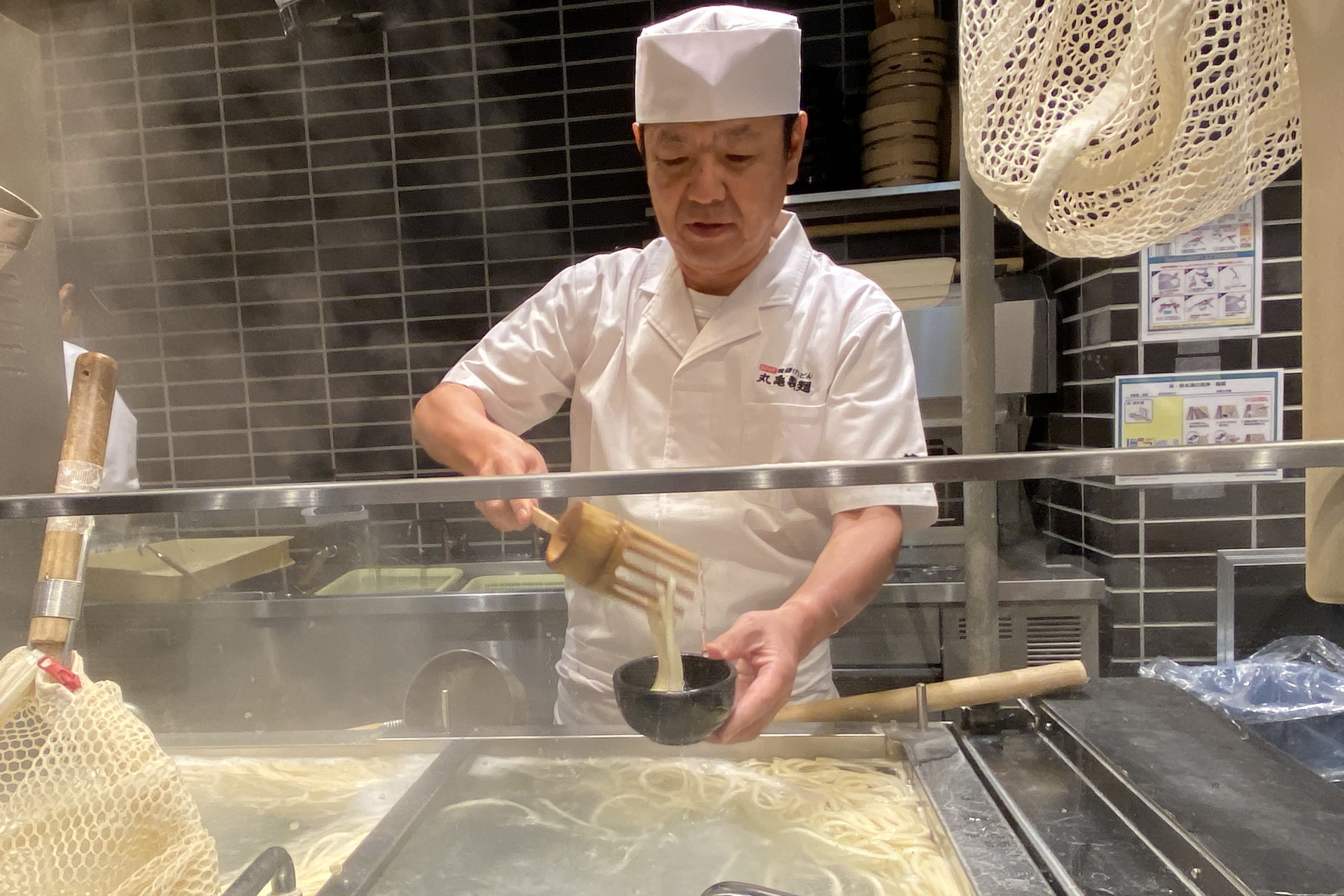 麺匠の藤本氏が「釜抜き麺」を実演調理。うどんカキを巧みに使い、手際よく麺をよそっていく