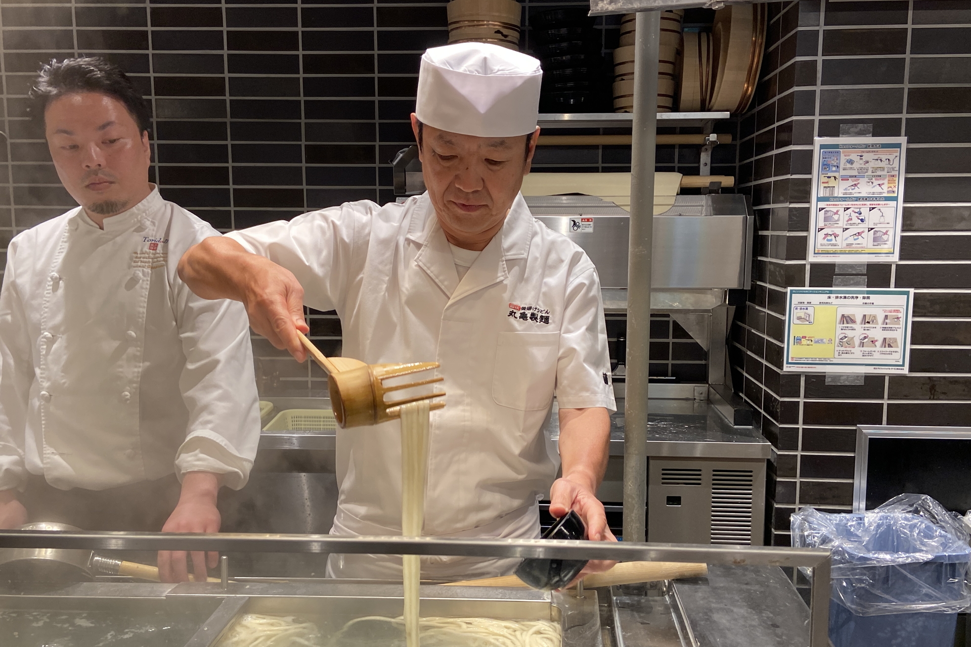 麺匠の藤本氏が「釜抜き麺」を実演調理。うどんカキを巧みに使い、手際よく麺をよそっていく