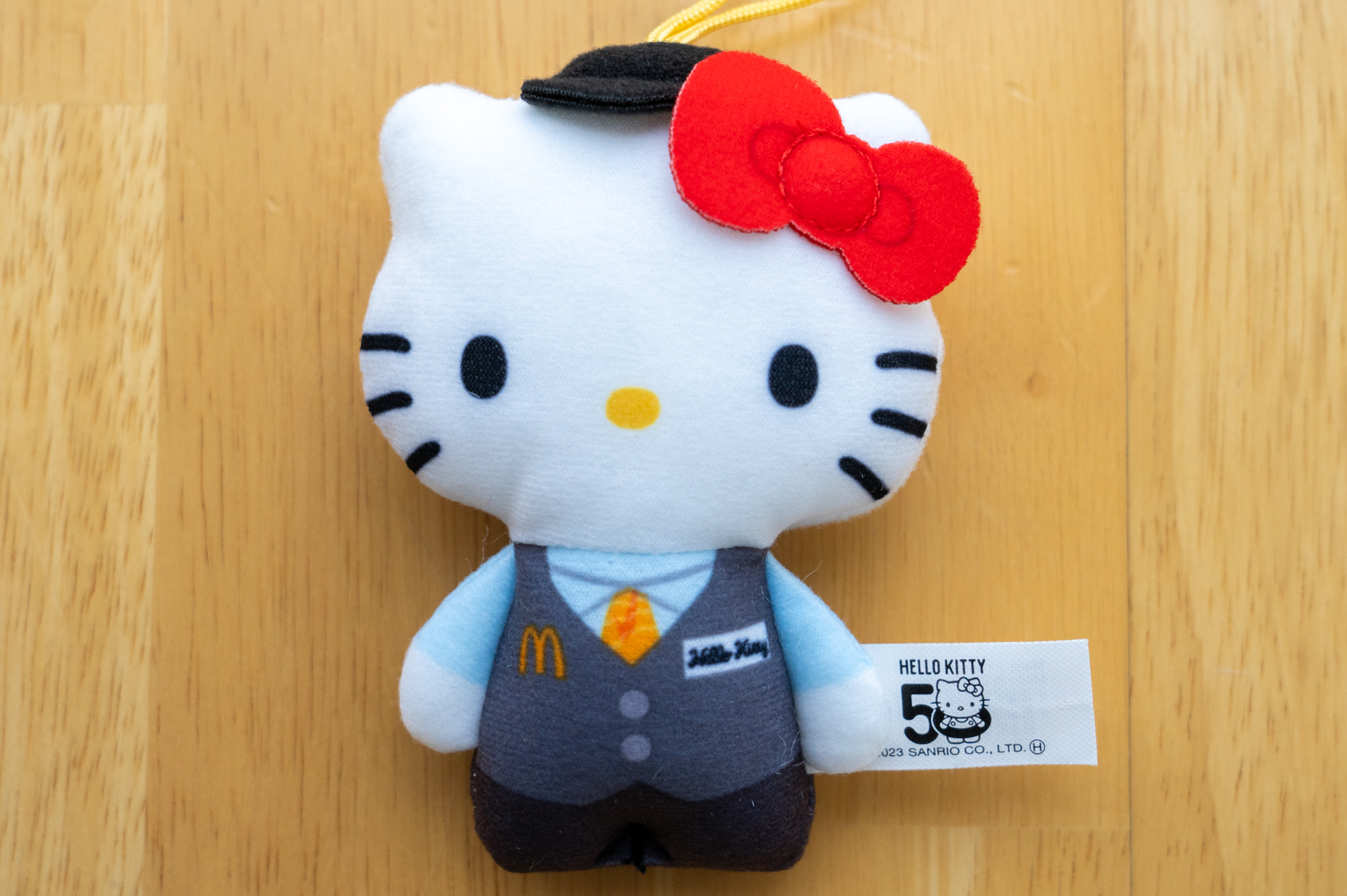 ハローキティ「マクドナルド限定マネージャー」。ブルーのシャツにグレーのベスト姿で、ネームタグには「Hello Kitty」と書いてある