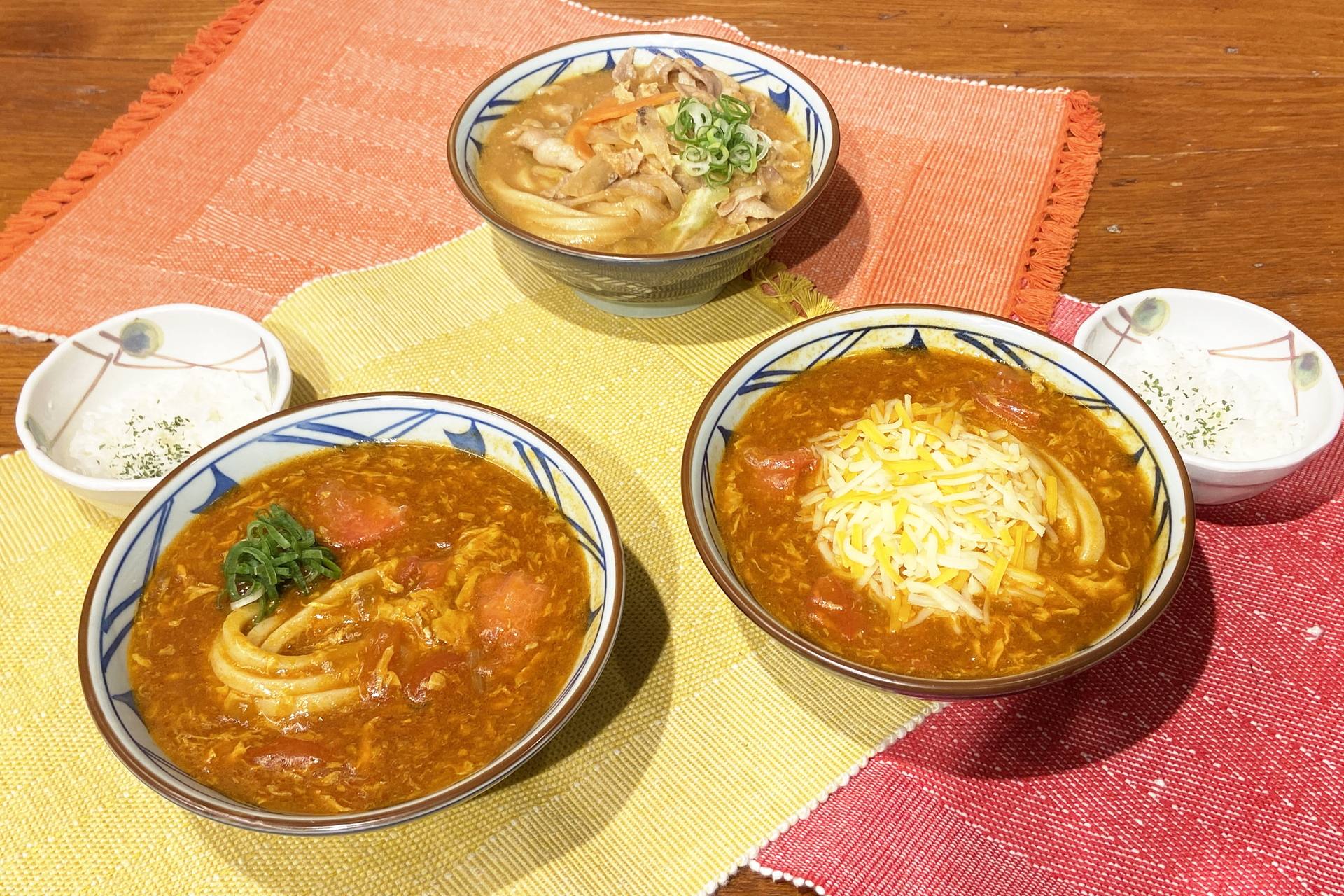 丸亀製麺×TOKIO「トマたまカレーうどん」（左）、「とろけるチーズのトマたまカレーうどん」（右）、「俺たちの豚汁うどん」（奥）