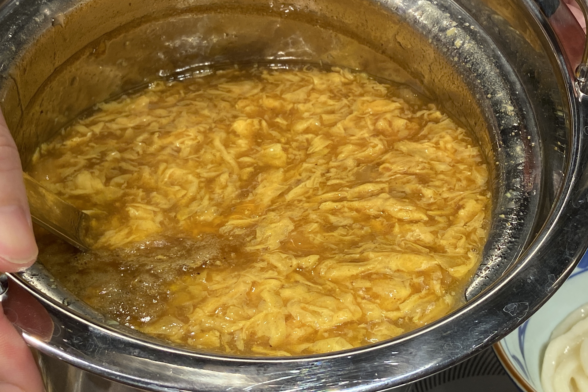 京風のカレーあんかけをベンチマークにしたカレーうどんの上に、塩胡椒とカレー粉で味つけした鶏天を3つ、カレー味のそぼろ、無塩バターをトッピング