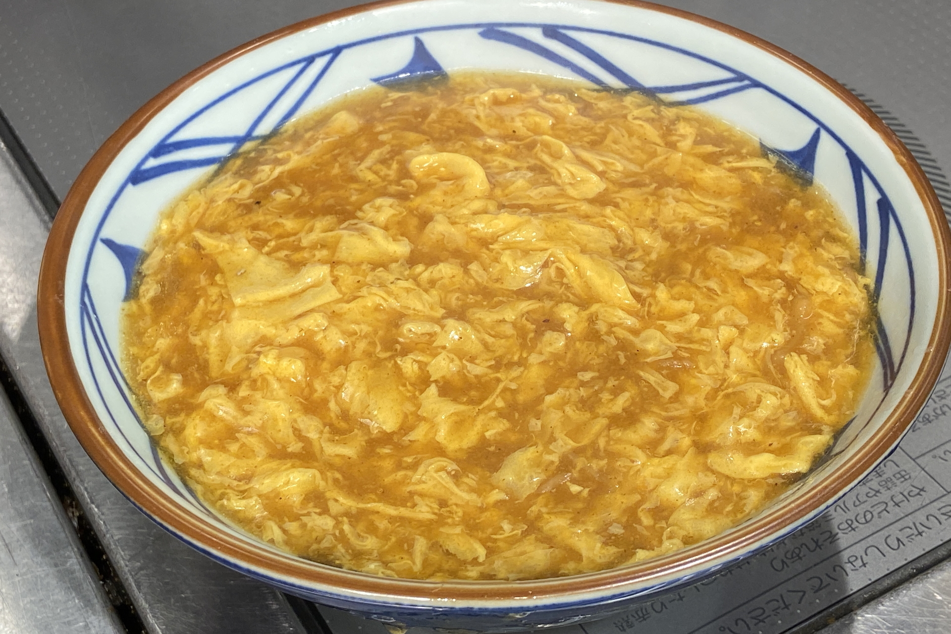 京風のカレーあんかけをベンチマークにしたカレーうどんの上に、塩胡椒とカレー粉で味つけした鶏天を3つ、カレー味のそぼろ、無塩バターをトッピング