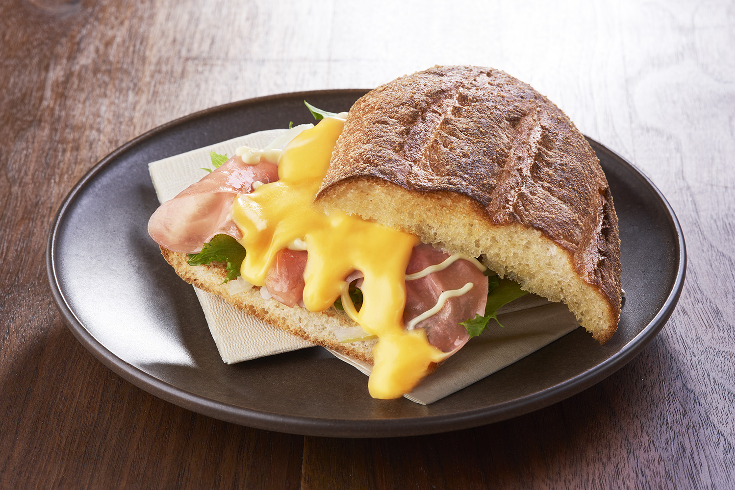 チェダーチーズの優しい塩味と柔らかいハムが魅力的で、フリルレタスや玉ねぎの食感がアクセントの「サンマルクホットサンド ハムチーズ」（490円～）