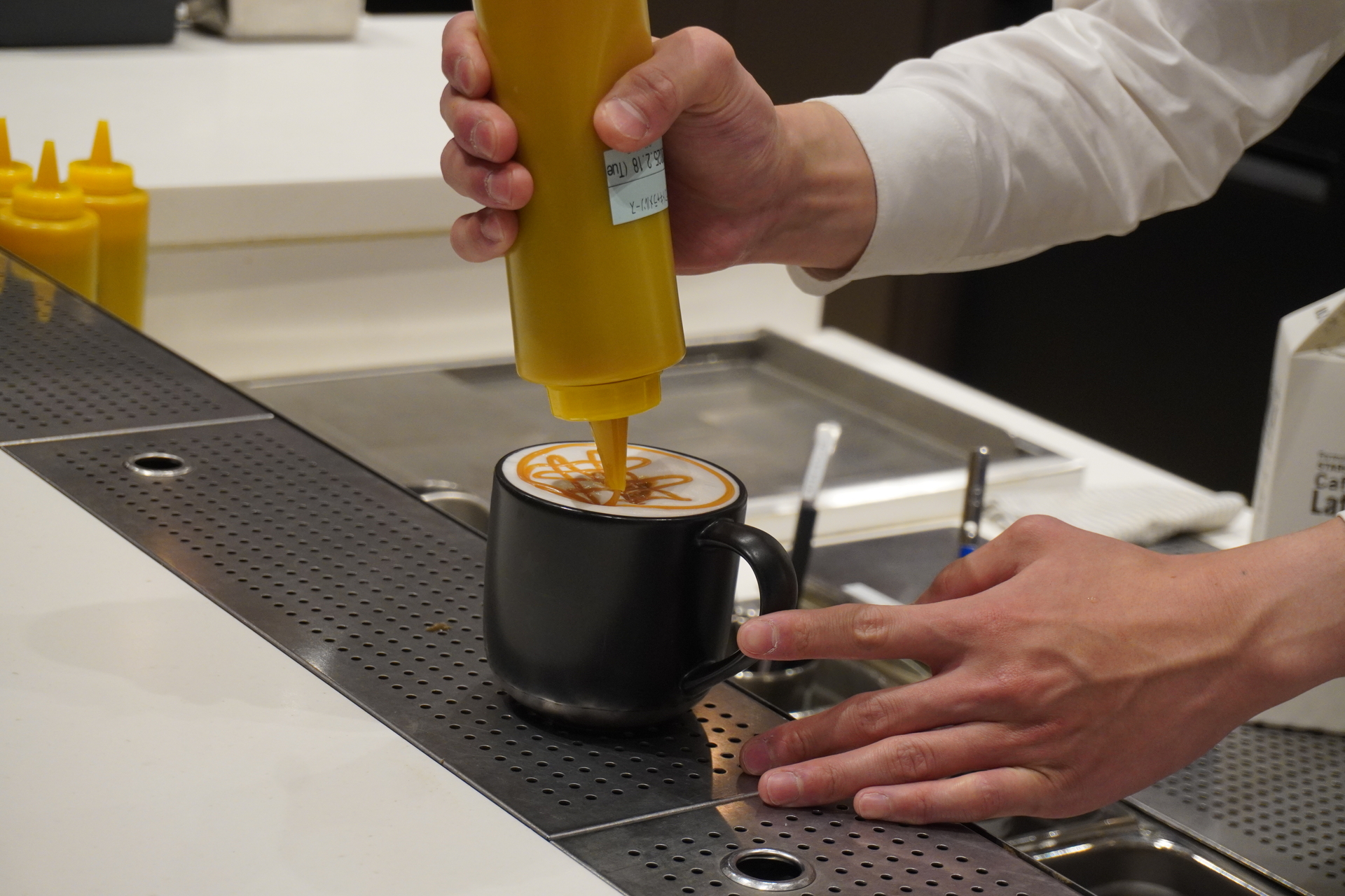 スターバックス リザーブ ストア 銀座マロニエ通りのパートナー 高橋丈さんが「ブラック イーグル」で抽出したエスプレッソを使った「GINZA ダブルトール キャラメル マキアート」の提供工程を実演した