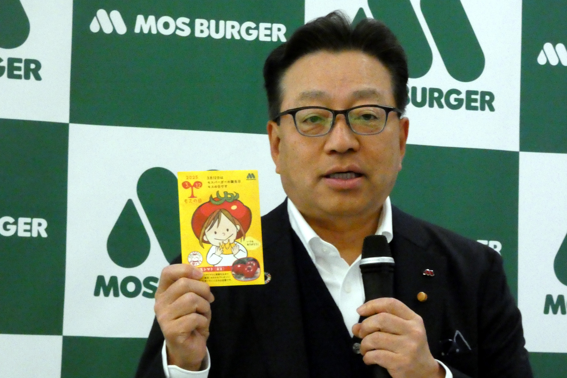 3月12日の「モスの日」にあわせて先着順で店頭配布している「大玉トマト麗夏の種」をアピールする代表取締役社長の中村栄輔氏