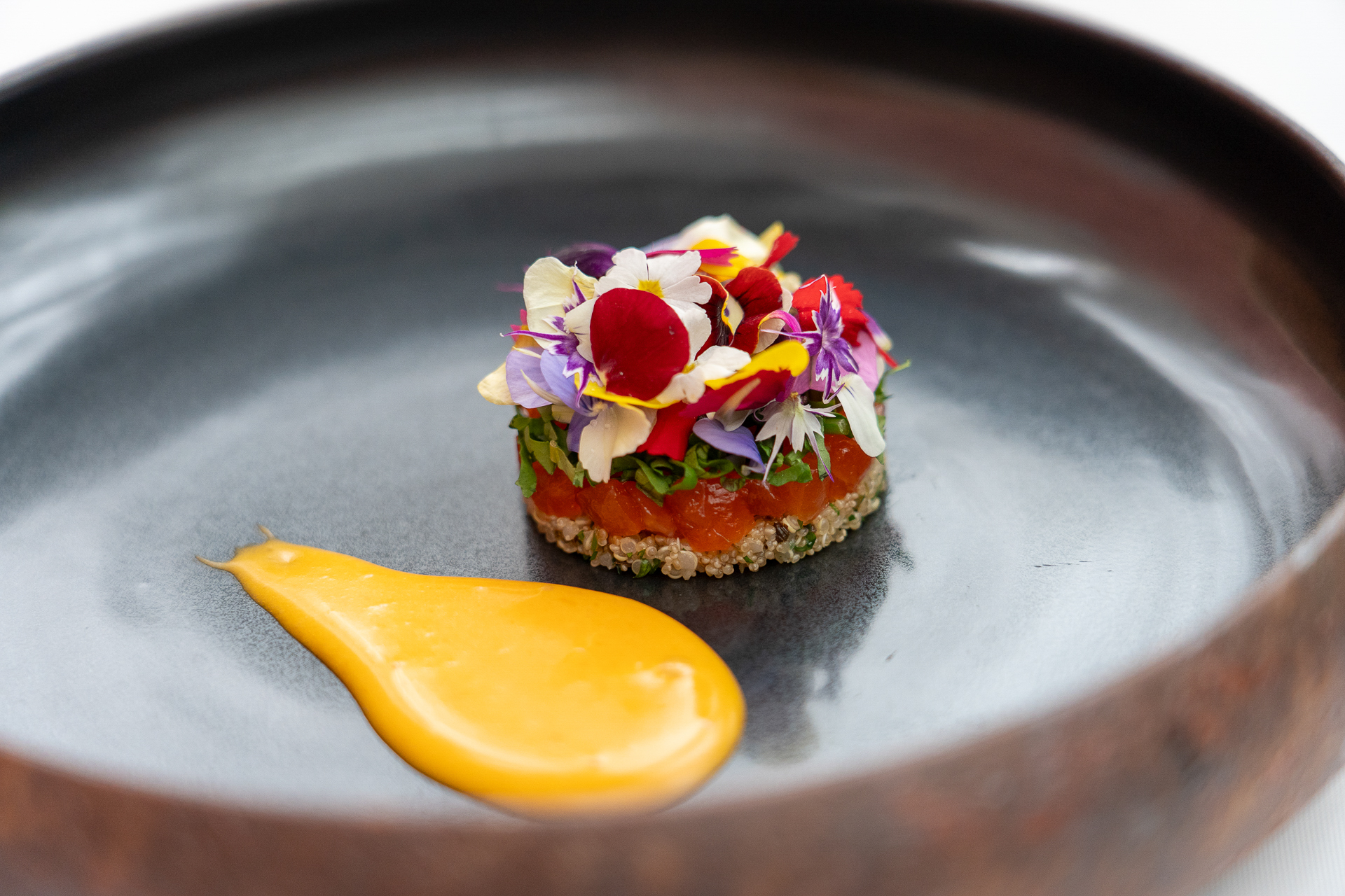 野菜畑のプレートの下に隠れていたのはエディブルフラワーをまとった「ニジマスのマリネ」。添えられているのは甲州味噌と卵黄を合わせたサバイヨンソース