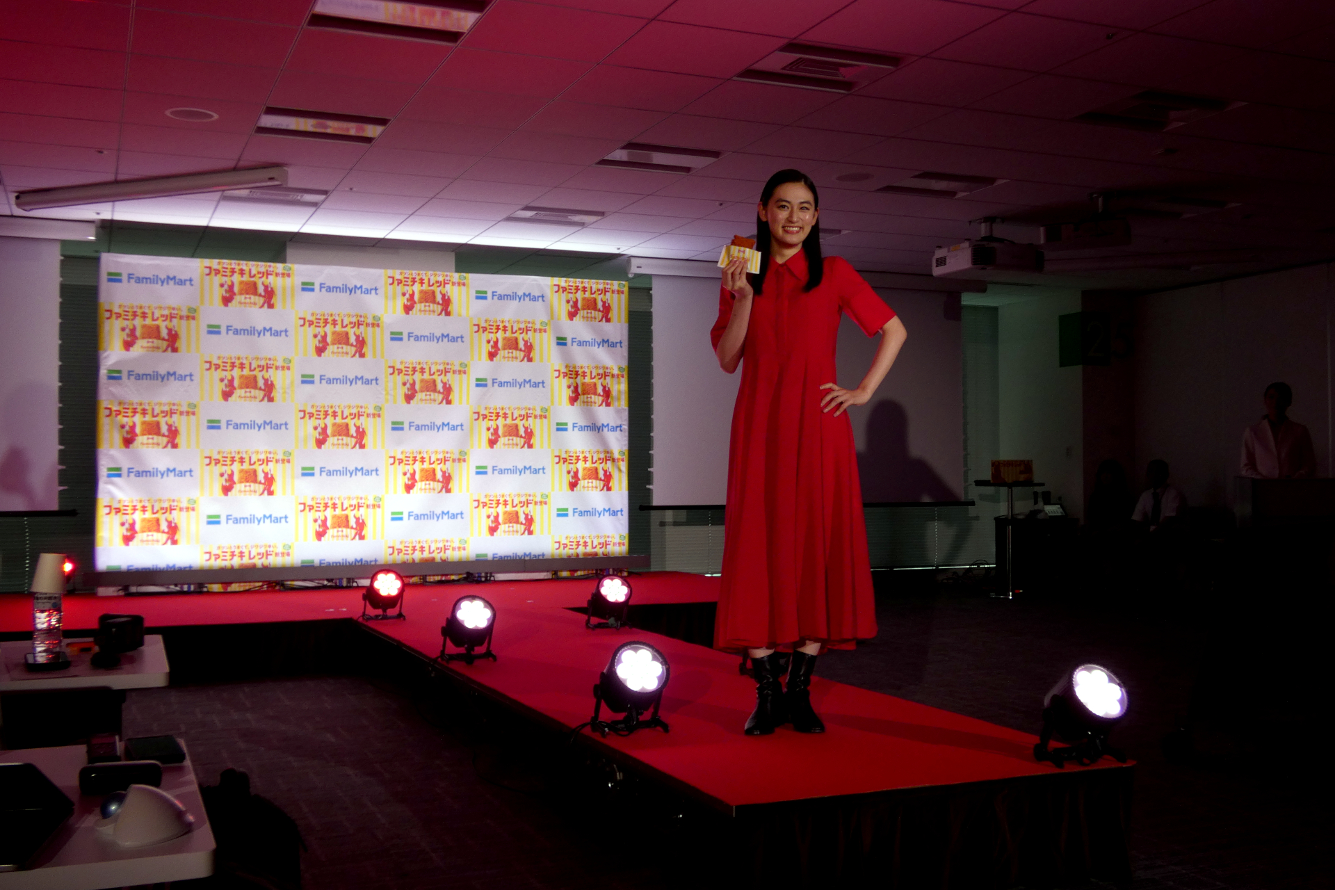 会議室内に設けられたランウェイをファミチキ レッドを手に歩く八木莉可子
