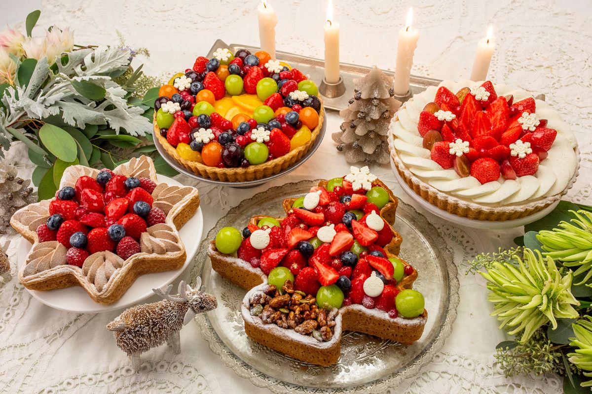 手前右から時計回りに「～タルトプレミエ～ クリスマスツリーのタルト」「新作 星型 赤いフルーツとチョコレートクリームのタルト」「色とりどりのフルーツリースタルト」「新作 ブルターニュ産 “ル ガール”クリームチーズと赤いフルーツのタルト」