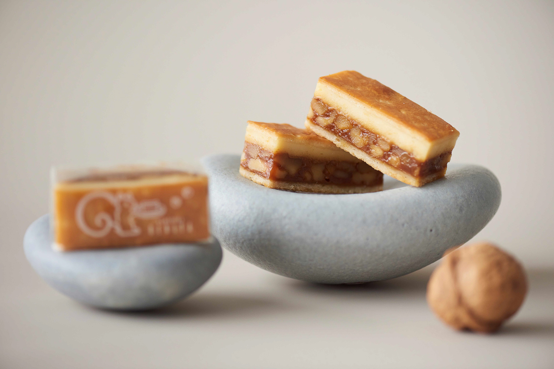 クルミをぎっしり詰め込んだ自家製キャラメルの上に、サワークリームと、クリームチーズをベースにしたトンカ豆が香る爽やかなチーズクリーム、通称「ミスチ クリーム」を塗り重ね、卵を使用しないバニラ風味の生地でサンドして焼き上げた