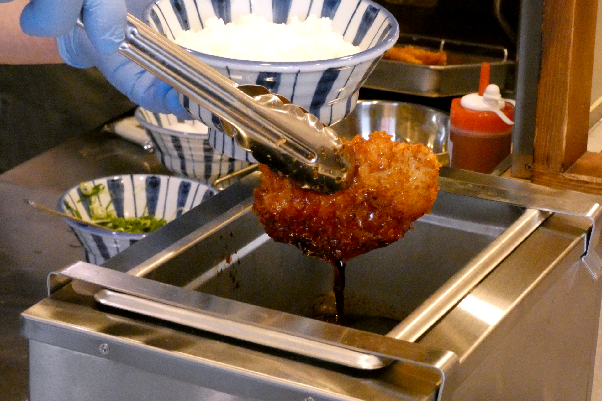 揚げたてのカツを特製のタレにぐぐらせて仕上げる