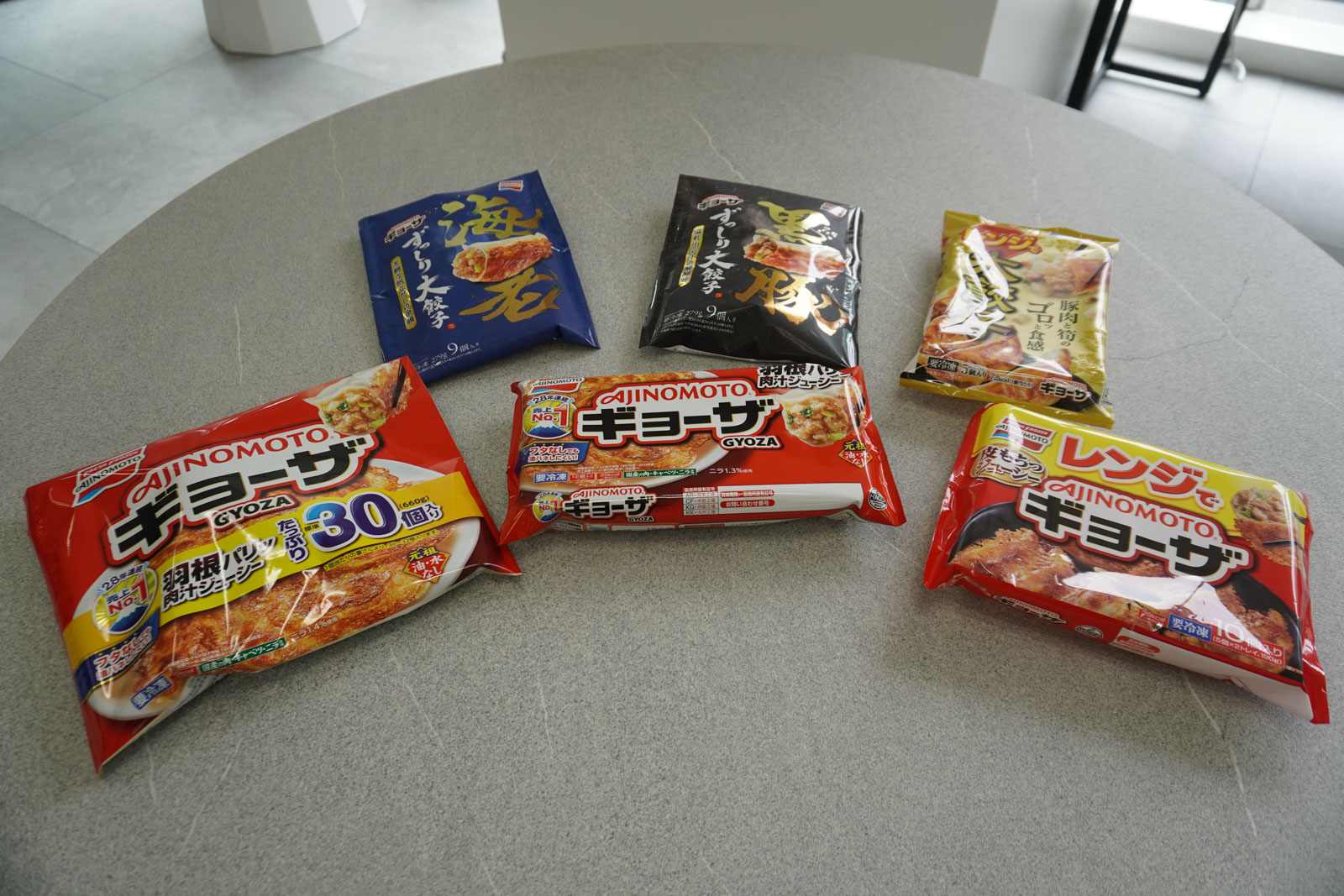 （手前中央から時計回りに）「AJINOMOTO ギョーザ＜ギョーザ＞（12個入り）」「同＜ギョーザ＞（標準30個入り）」「同＜ずっしり大餃子 海老＞」「同＜ずっしり大餃子 黒豚＞」「同＜レンジで大餃子＞」「同＜レンジでギョーザ＞」