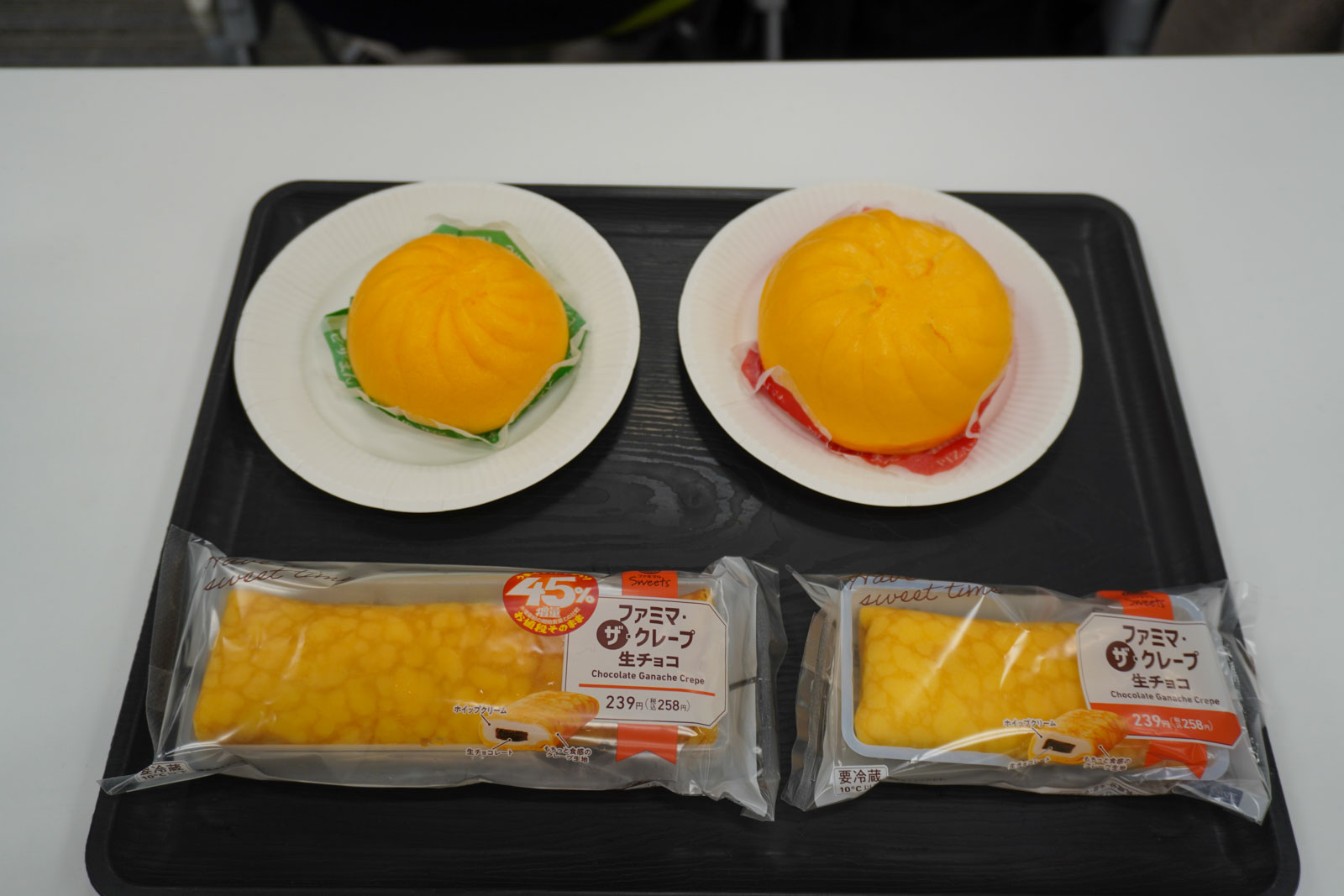 試食で提供された「のびーるチーズのコク旨ピザまん」（右が増量商品）と「ファミマ・ザ・クレープ　生チョコ」（左が増量商品）