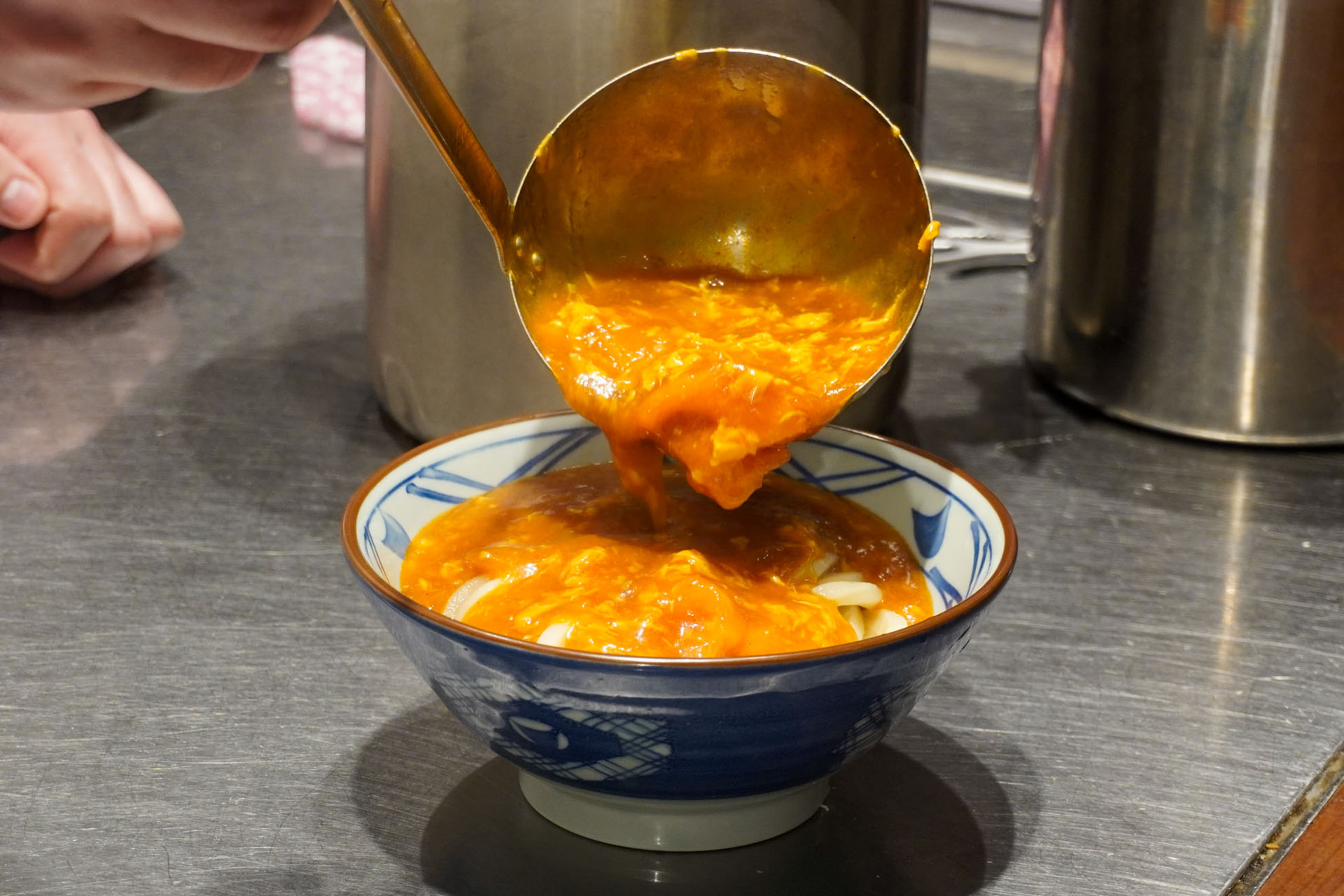 丼にうどんを盛り、トマたまカレーをかける