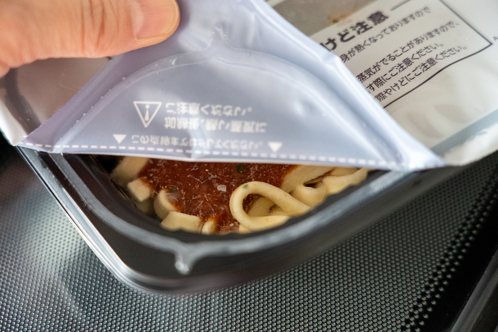 外袋から出してトレイのフタを左下の点線まではがし、電子レンジで温めます（500Wで約5分10秒、600Wで約4分30秒）