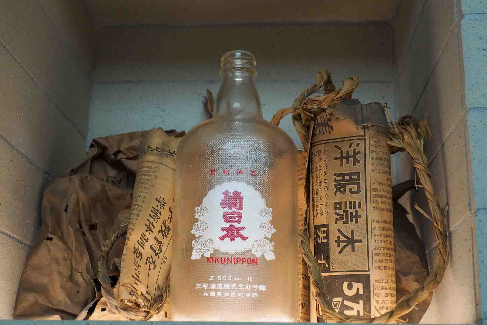 段ボールがなかった時代、破損を防ぐため藁で巻いて運ばれた創業銘柄「菊日本」のボトルと推定84年前の新聞