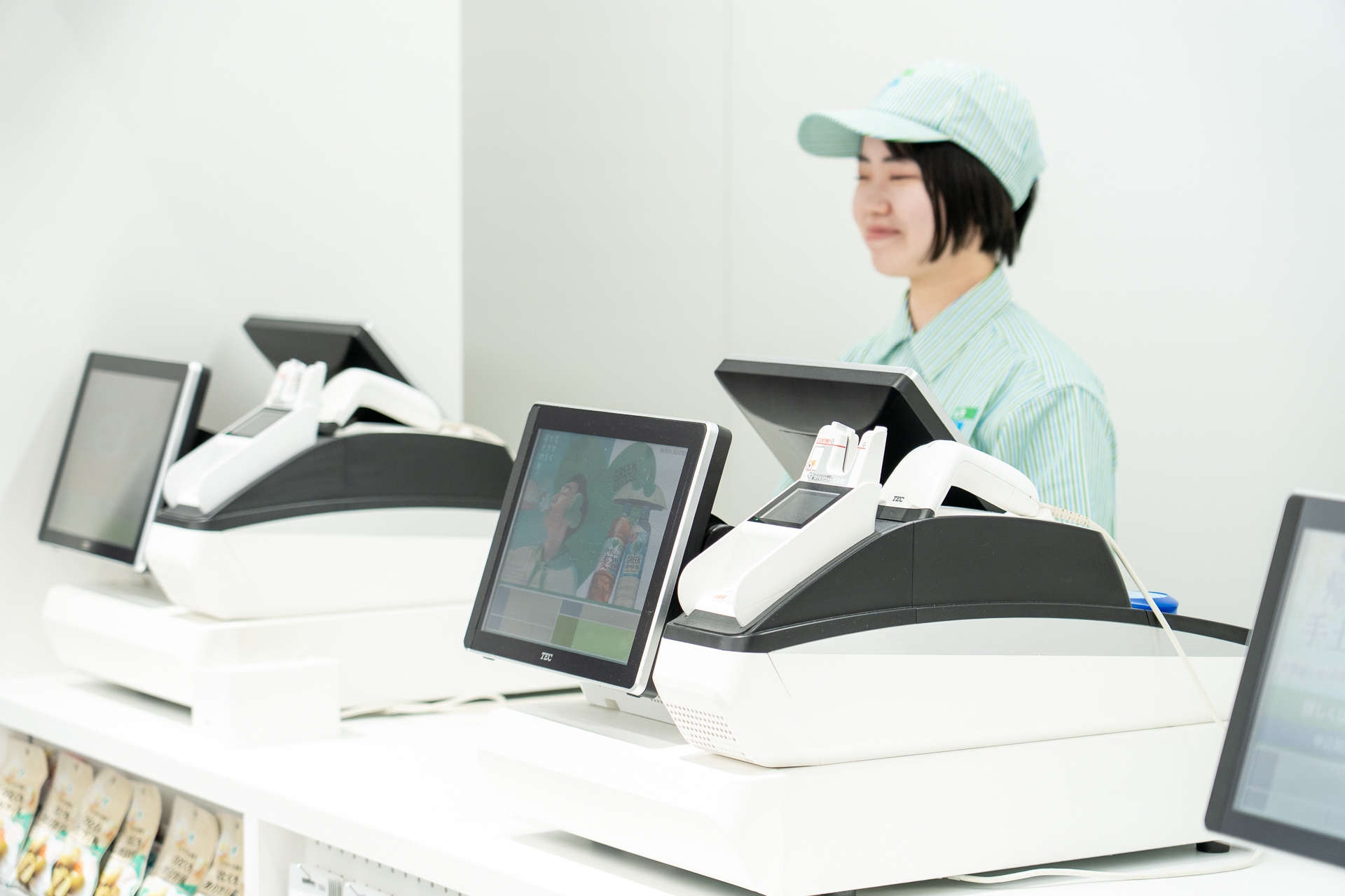 有人レジカウンター。スタッフはミントグリーンのストライプ柄ユニフォームとキャップを着用