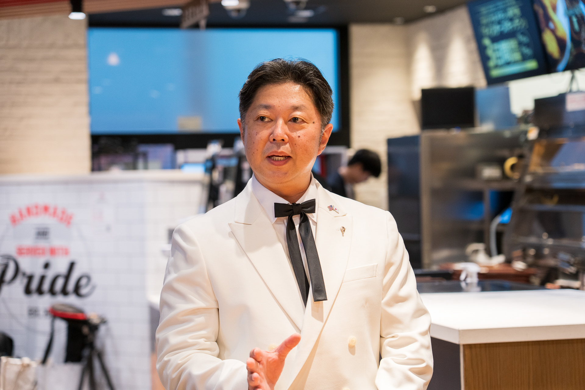 チキンマイスターの笠原一樹氏。カーネル・サンダース人形と同じ白いスーツ姿！