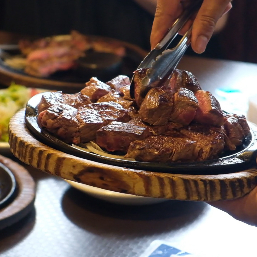焼きたてのステーキをスタッフが店内を回りながら各テーブルでサービス