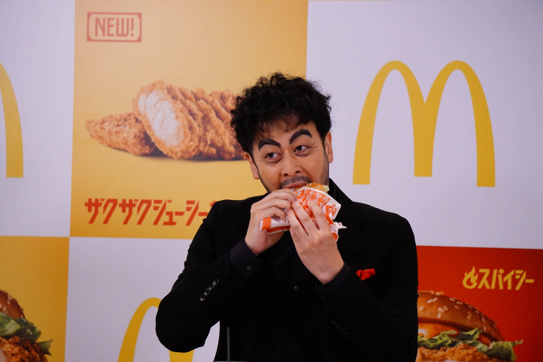 「スパイシーザクザクジューシーマック」を試食する都留さん