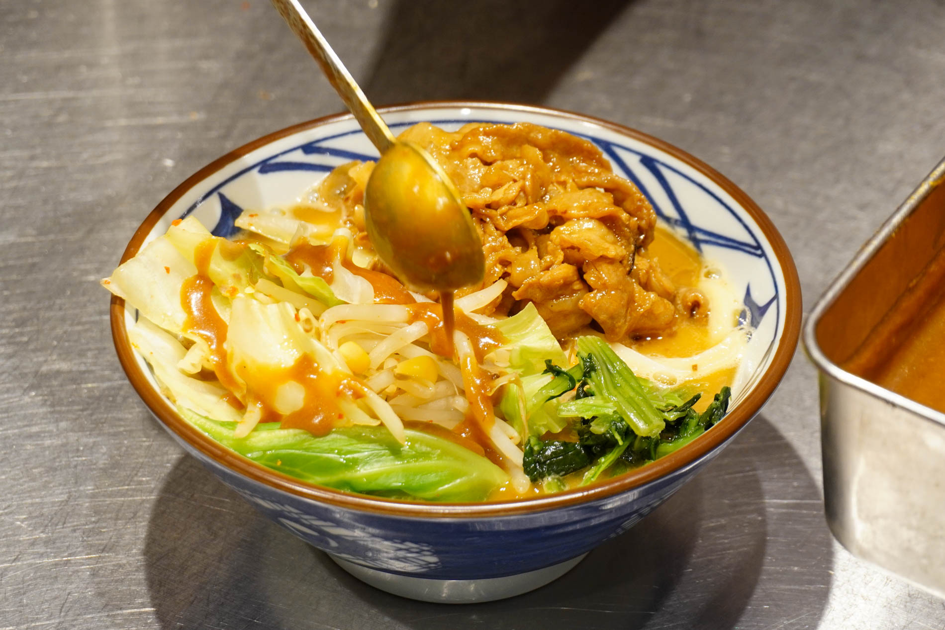 味噌だれを丼に回しかける