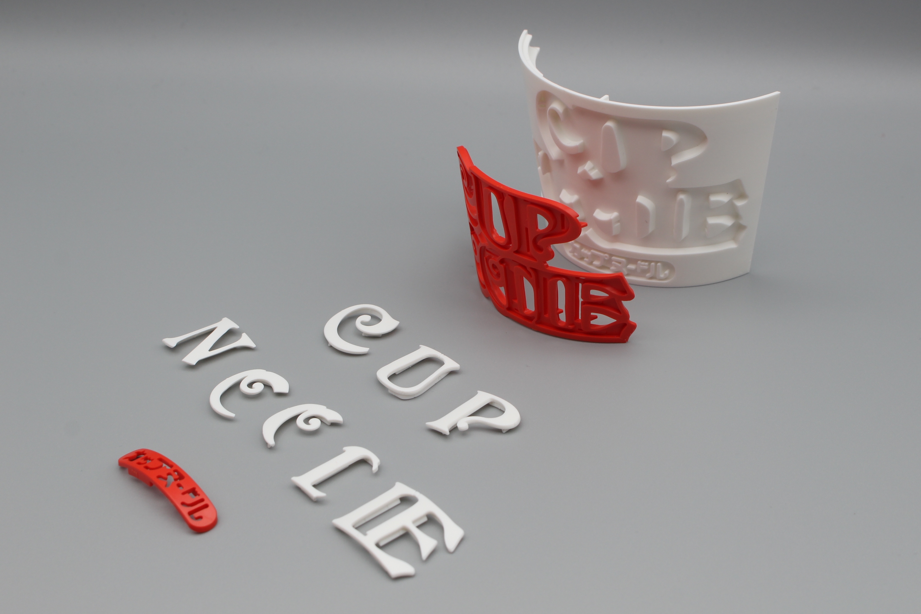 ロゴとカップ前面のパーツ群。ロゴはベースに合うように湾曲している