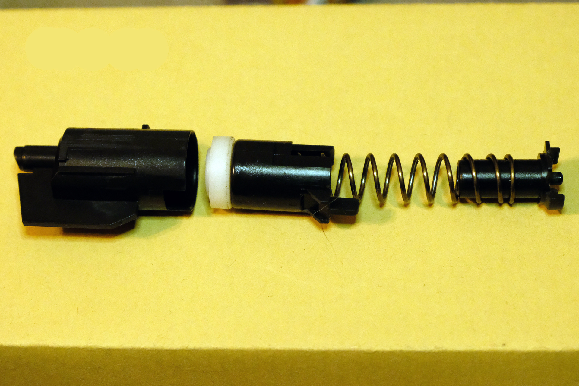 左がシリンダーと呼ばれる筒。真ん中がピストンで先端には柔らかなピストンカップが付いている。右がスプリング。手動で縮めた（コッキング）スプリングが解放されるとピストンを押し、ピストンカップがシリンダーの内圧を高めて、放出された空気圧がシリンダーの先端から噴出してBB弾を飛ばす