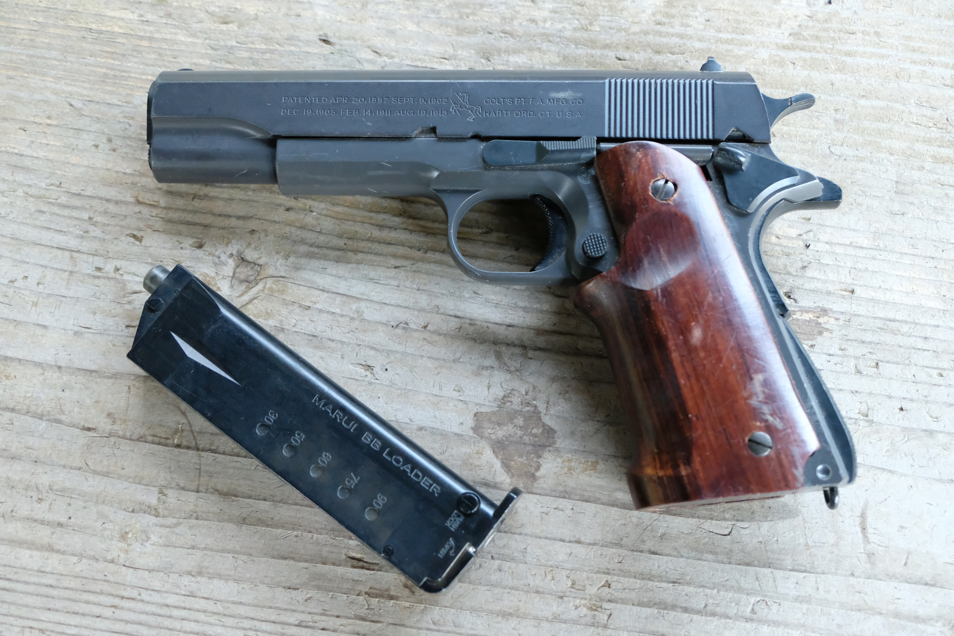 筆者が18年来愛用のエアーハンドガン「M1911A1 ガバメント」とBBローダー。グリップをリアルウッドに変えた以外は完全ノーマルだ