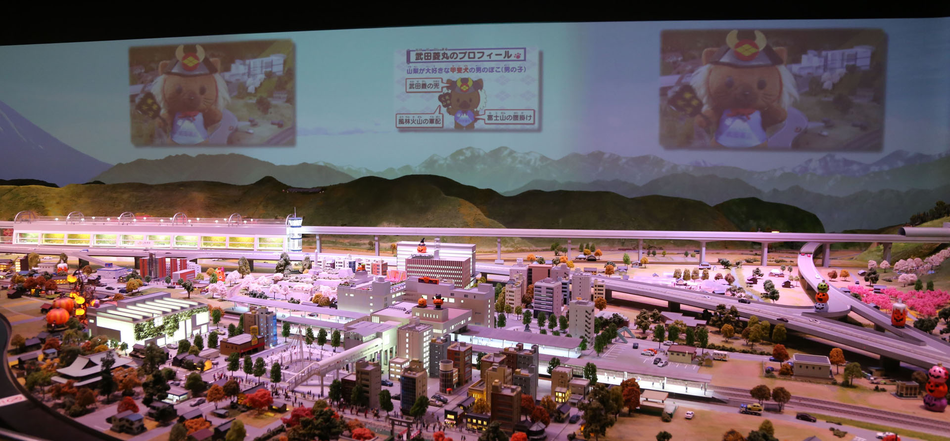 手前が甲府駅。奥の左側がリニア中央新幹線山梨県駅のイメージ。背面のスクリーンは富士山や空を映すほか、演出に合わせた動画を再生する