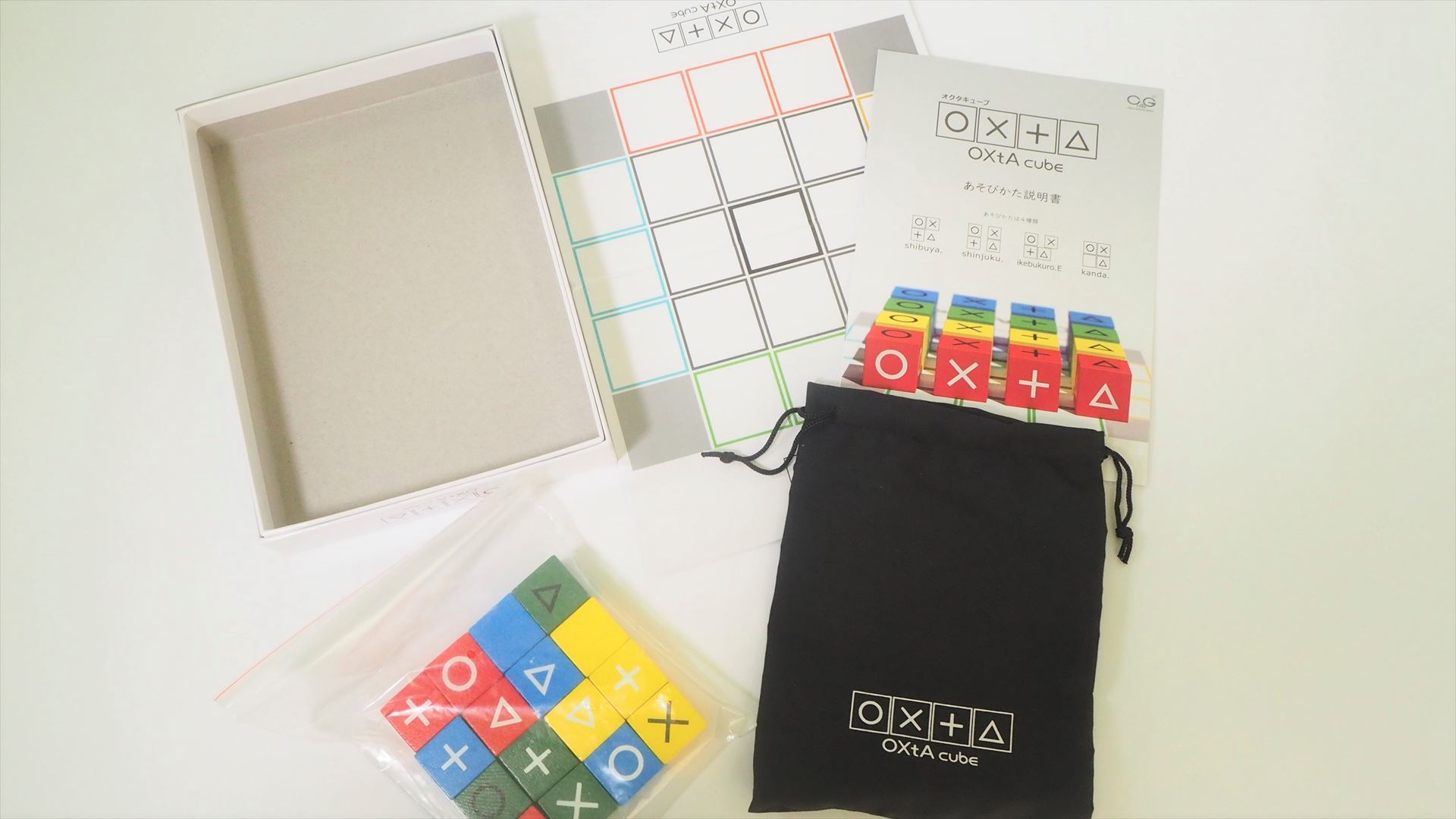 「OXtA cube」のパッケージ内容。16個の木製キューブコマとゲーム用ボード、キューブコマ用ポーチ、遊び方説明書が入っている