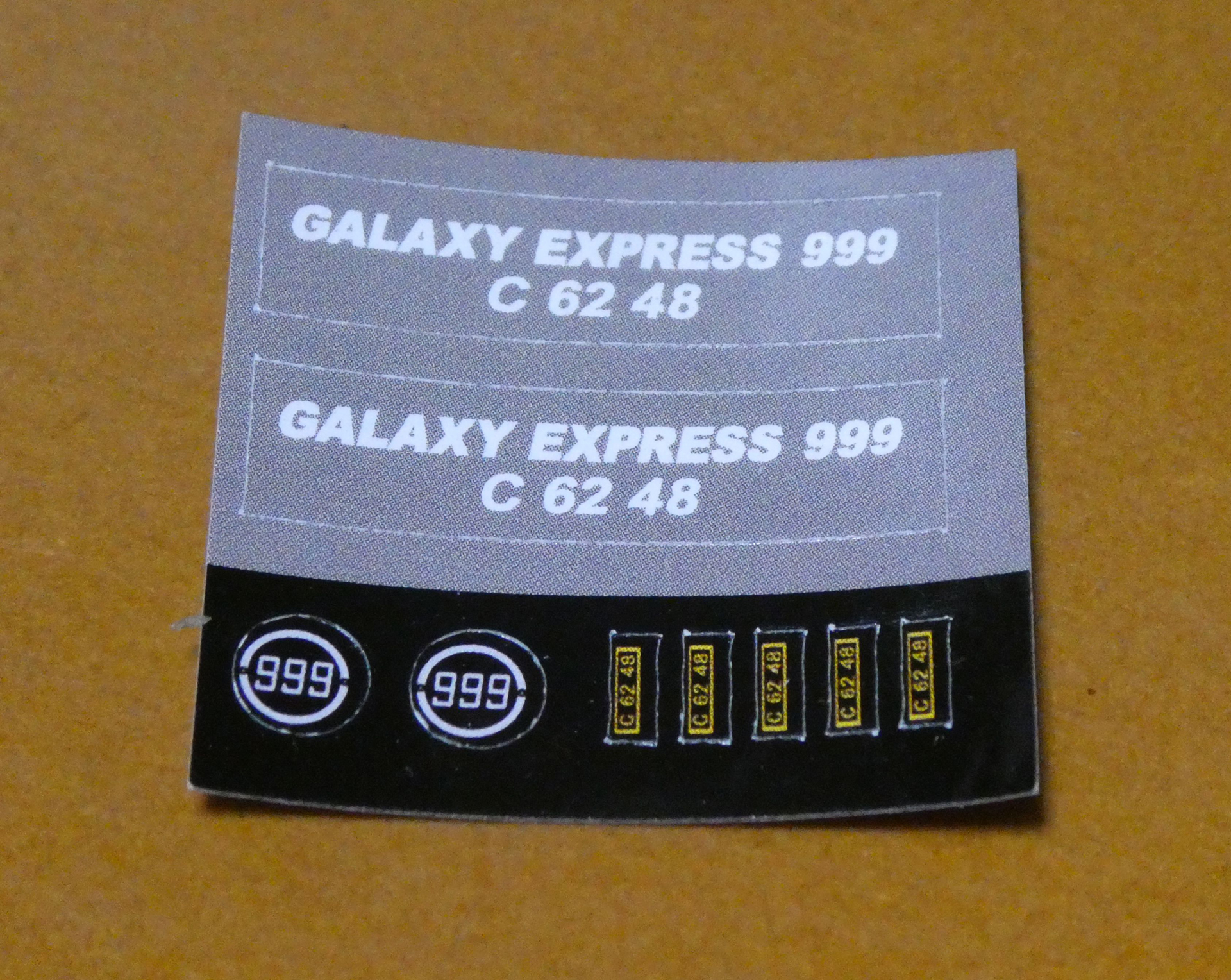 上半分の灰色は台座に貼るシール、下半分の黒色は機関車に貼るシール