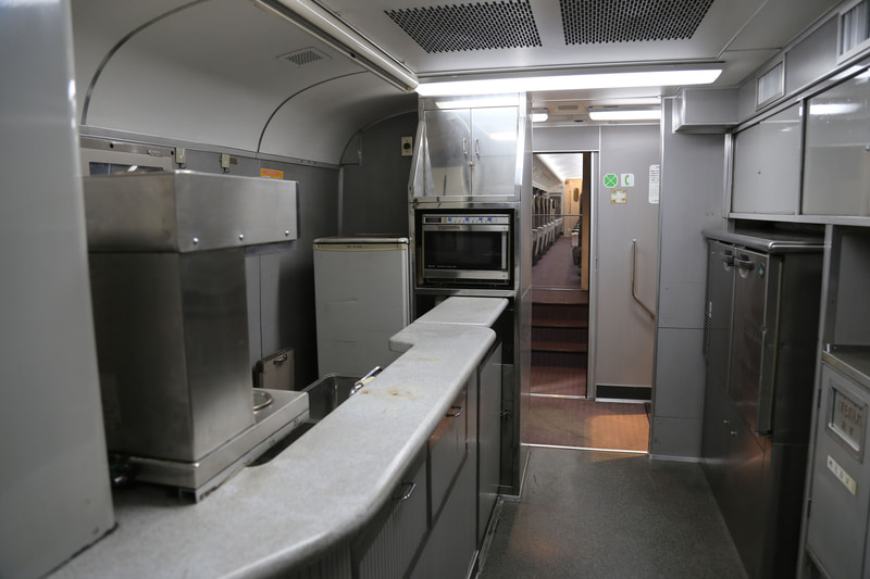 ダブルデッカー車両の内部。手前が車内販売準備用のサービスコーナー。奥の通路が2階席に通じている。グリーン車のマークがある