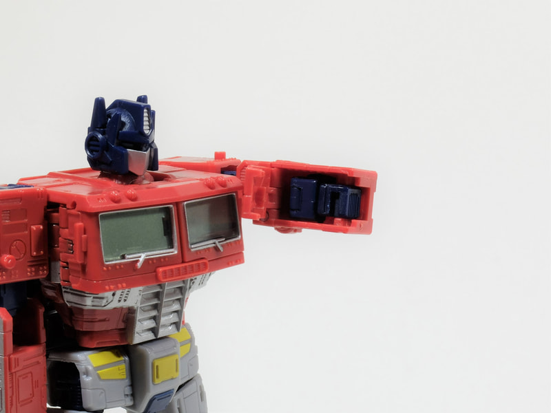 手順は人によって異なると思うが、何はなくともまずは拳を収納するところから。上腕部の1辺が開閉するため、そこを開いて拳を収納する。この時、拳の向きによっては開閉部と干渉する場合があるので、拳の向きを手の甲が開閉部を向くように整えておく。肘は正面に向けて90度にまげて、肩はトランスフォーム最後の収納時に備えて背中まで回転させておく。