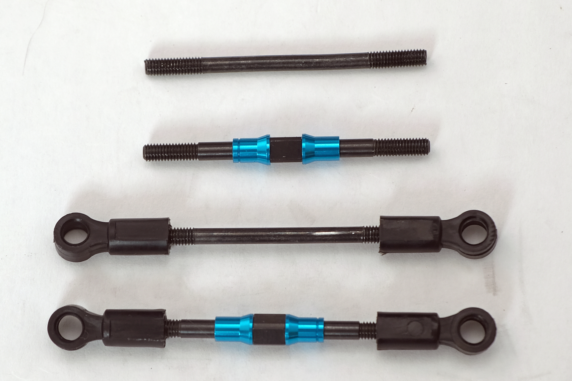 ノーマルシャフト（1番上と3本目）とハードターンバックルシャフト（2本目と4本目）の比較。ターンバックルシャフトは左右のネジ部が逆ネジになっている。黒い樹脂のアジャスターは付属していないので、逆ネジにする為に新しい物が必要になる。筆者はステアリングワイパーセットで使った物をそのまま流用した