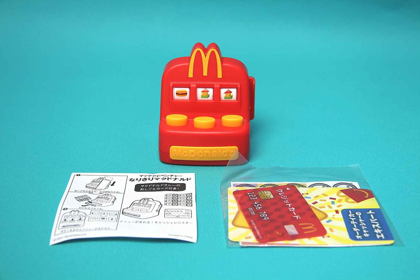 「メニューがまわる！キャッシュレジスター」のセット内容。基本はおもちゃと説明書、袋に入った小物類がセットになっている