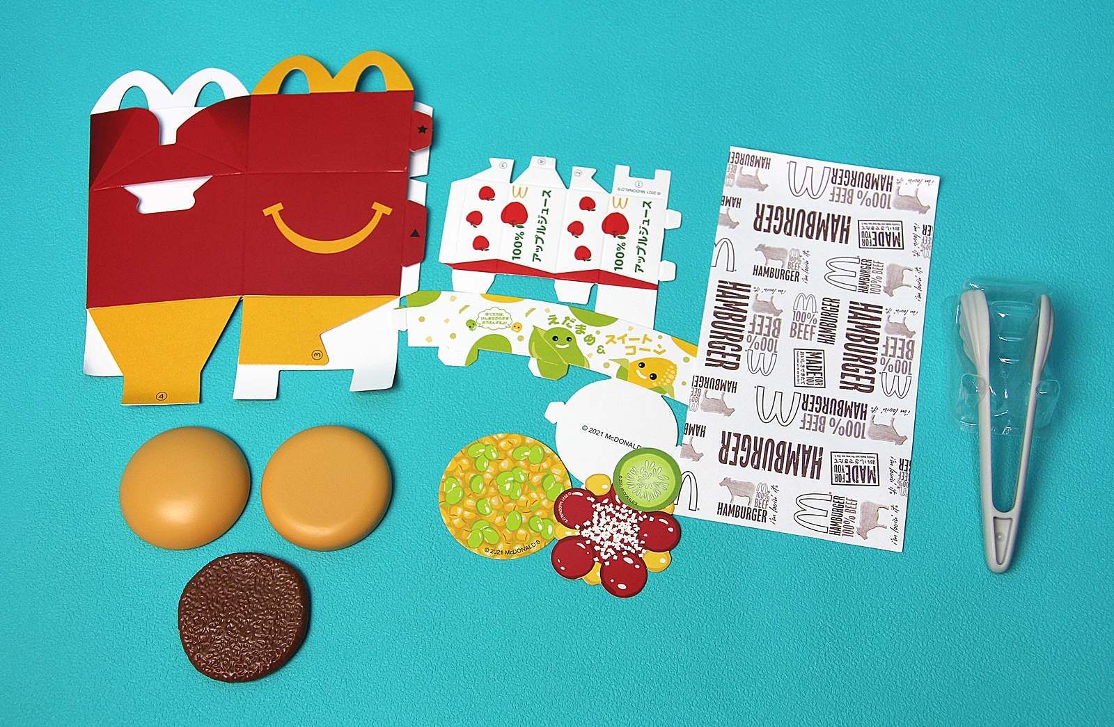 プラスチック製のバンズやトング、ペーパークラフトのハッピーセットボックスなど、いろいろなアイテムが詰められている