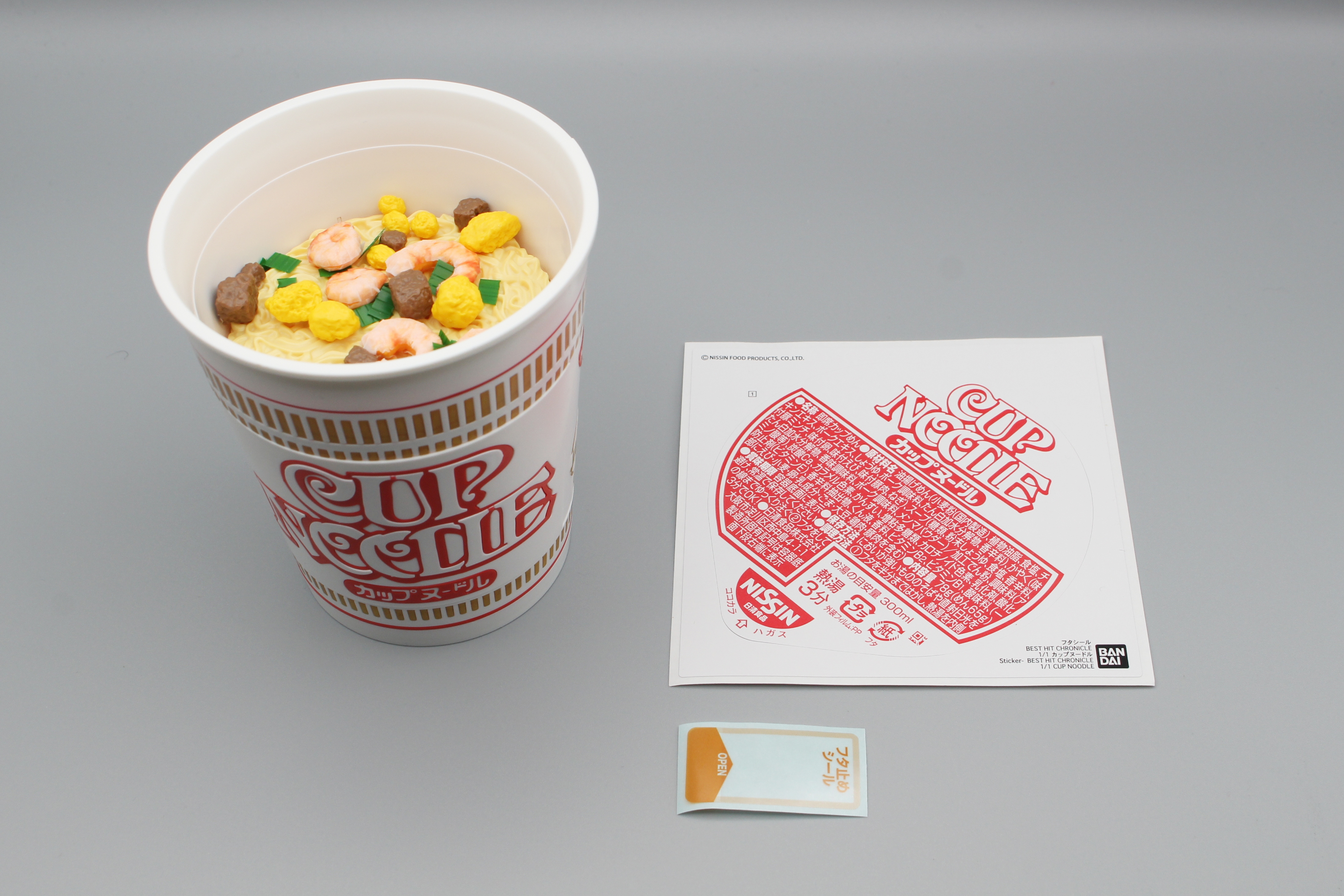 「フタ止めシール」はBANDAI SPIRITSが2020年9月に発売したプラモデル「BEST HIT CHRONICLE 1/1 カップヌードル」にも付属していた。「カップヌードル」が大幅なバージョンアップならプラモデルの新バージョンにも期待したい