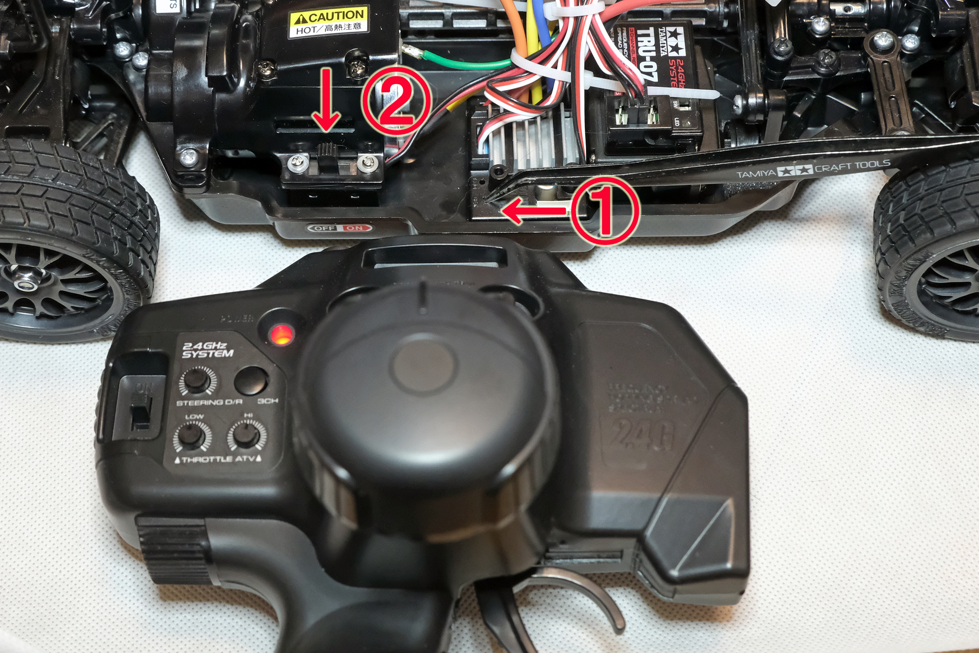 送信機の電源をONにした後に、1のセットボタンをピンセットなどで押しながら、2の受信機スイッチをオンにする