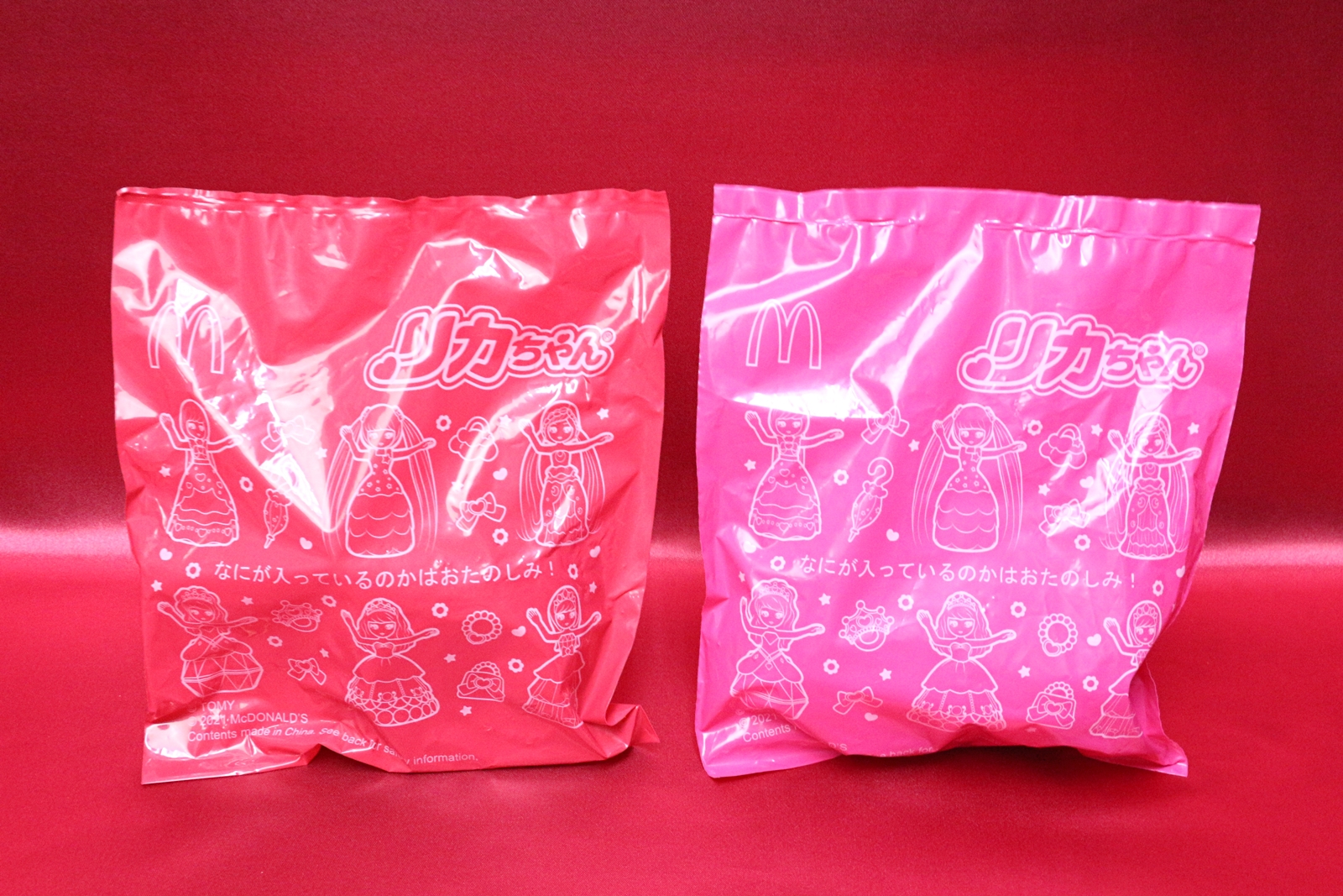 おもちゃ袋。赤色の袋が第1弾、ピンク色の袋が第2弾となる