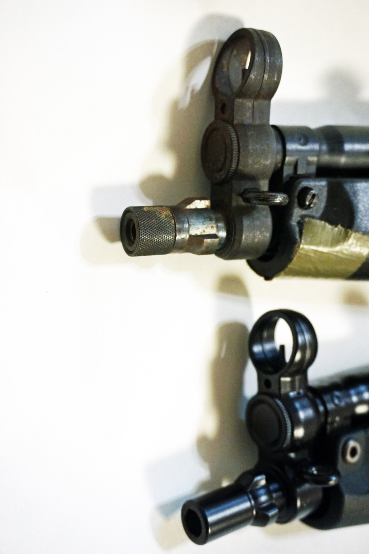 因みに筆者所有の「スタンダードMP5A4」のフロント部分(画像上)はロストワックス成型の鋳鉄によるフロントサイトベースと、スチール削り出しで黒染めしたマズル部に交換してある。しかし本物とは似ても似つかない質感だ。まさに「コレジャナイ」だが、その理由が20年越しで腑に落ちた