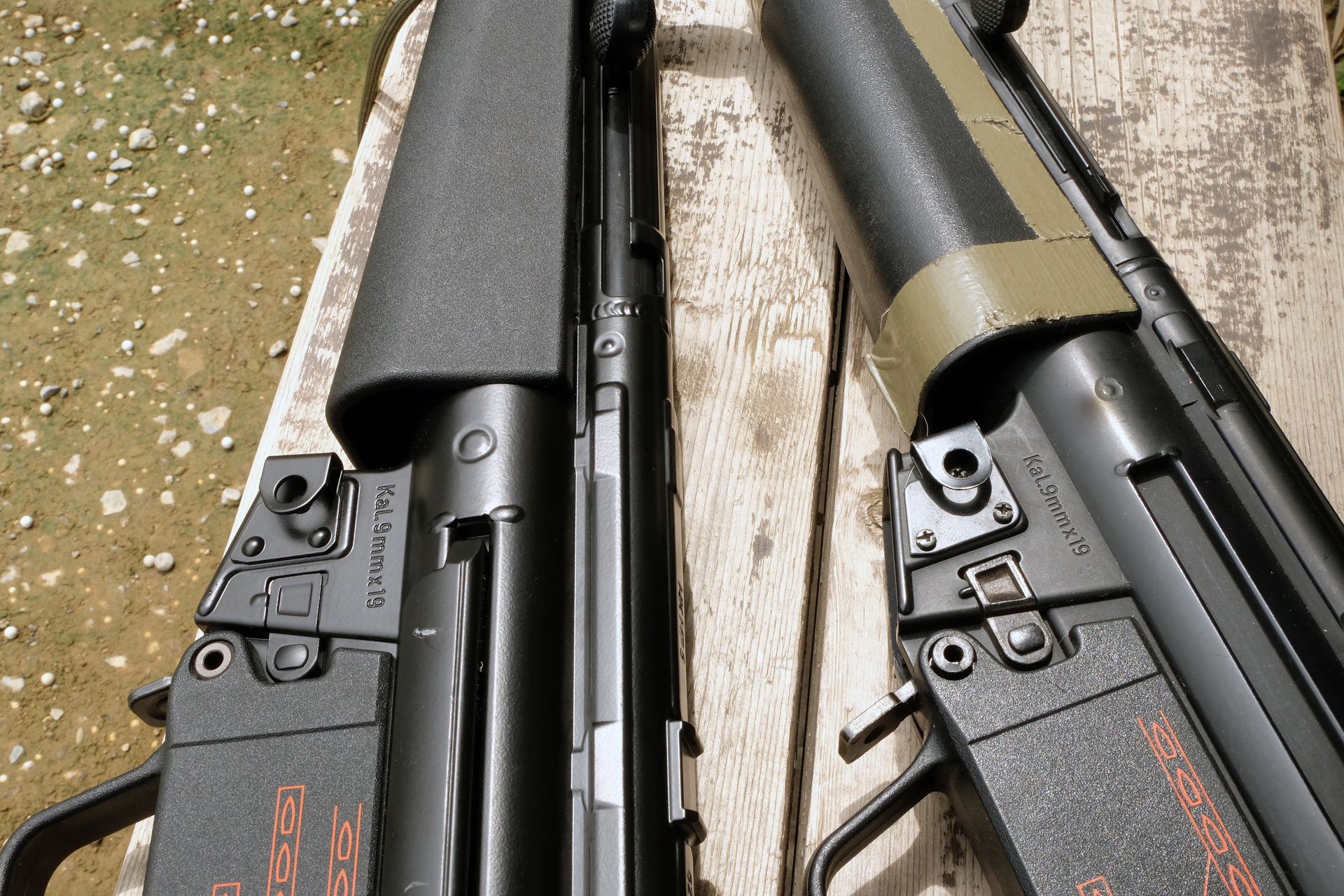 マガジンハウジング部。「スタンダードMP5A4」（向かって右）は、三角形の「スリングクリップ」がネジ止めだった。ハンドガードにはガムテープを雑に貼ってカモフラージュを施しているが、「次世代電動ガン MP5A5」（向かって左）の本物同様の素材で成型されたハンドガードと比べると「本物感」で遠く及ばない