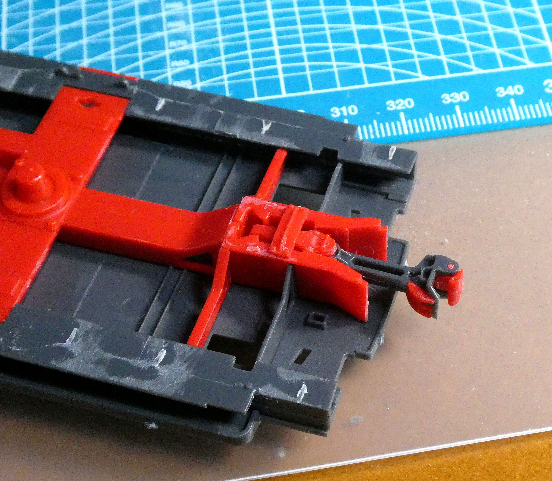 連結器は強固な台枠に取り付けられる。上下左右に動かせる。「走らせる鉄道模型」では走行安定のため台車に取り付けるけれど、プラモデルでは正規の位置になる